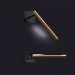 Oluce Ilo 187 lampada parete, Design David Lopez Quincoces, 2019. Lampada orientabile a luce led diretta, una barra di alluminio anodizzato sagomato in bronzo satinato, struttura a parete verniciato nel colore nero opaco. Ilio viene proposta in tre modelli: a sospensione, sospensione con movimento verticale e parete. Caratteristica di tutti i modelli il disegno longilineo ed elegante della barra in alluminio che accoglie la fonte luminosa LED. Ilo a parete, ha le stesse dimensioni della versione con movimento verticale, è fissata al muro attraverso una placca quadrata, snodandosi grazie ad un perno che ne permette l’orientamento in tutte le direzioni  grazie anche al corpo illuminante ruotabile di 90 gradi.