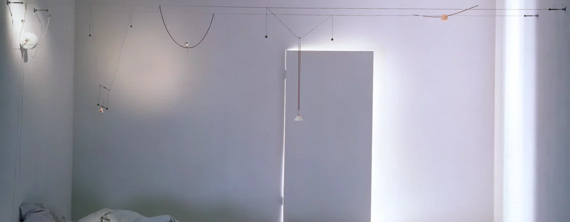 Sistema di illuminazione a cavi YaYaHo di Ingo Maurer installato in una camera da letto